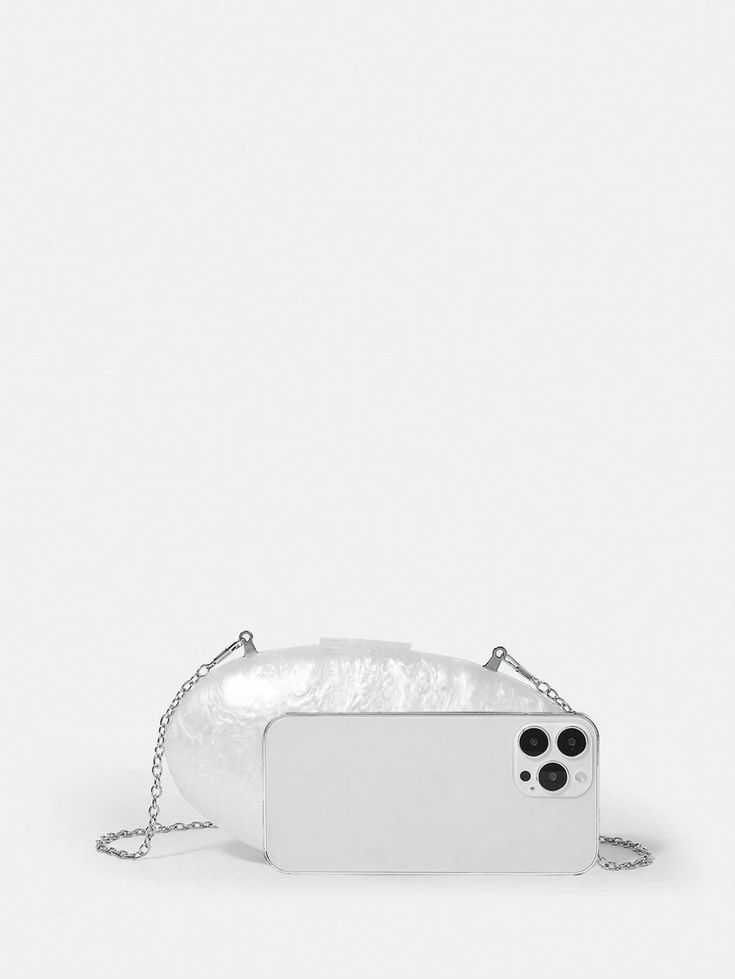 Our Ariel acrylic bag next to an iPhone for size comparison. Highlighting its compact size with a glossy finish and oval shape bag. Showing you can fit your phone and make up essentials for your next event with this clutch. Shown here with shoulder chain option.
