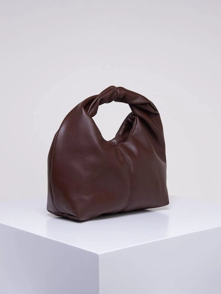 Our rich chocolate PU leather bag shown on an angle against a white background, highlighting the shape and feel of the bag. Handle is a thick relaxed style, perfect to pop over the forearm. Adding luxury to any outfit.