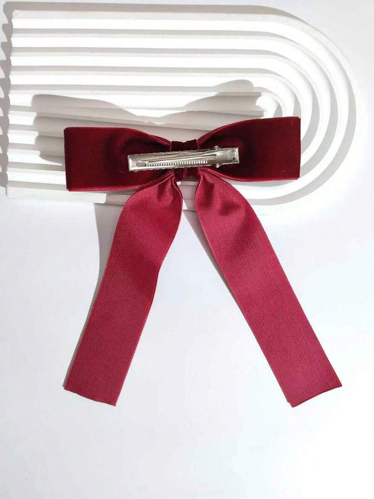 Our Plum velvet bow hair clip, laying flat on a Neutral background. Plush velvet material with a double layer of fabric at the top of the bow. Highlighting the back of the clip, showing the clasp and quality. Perfect for a wedding or a formal affair adding a luxurious touch.