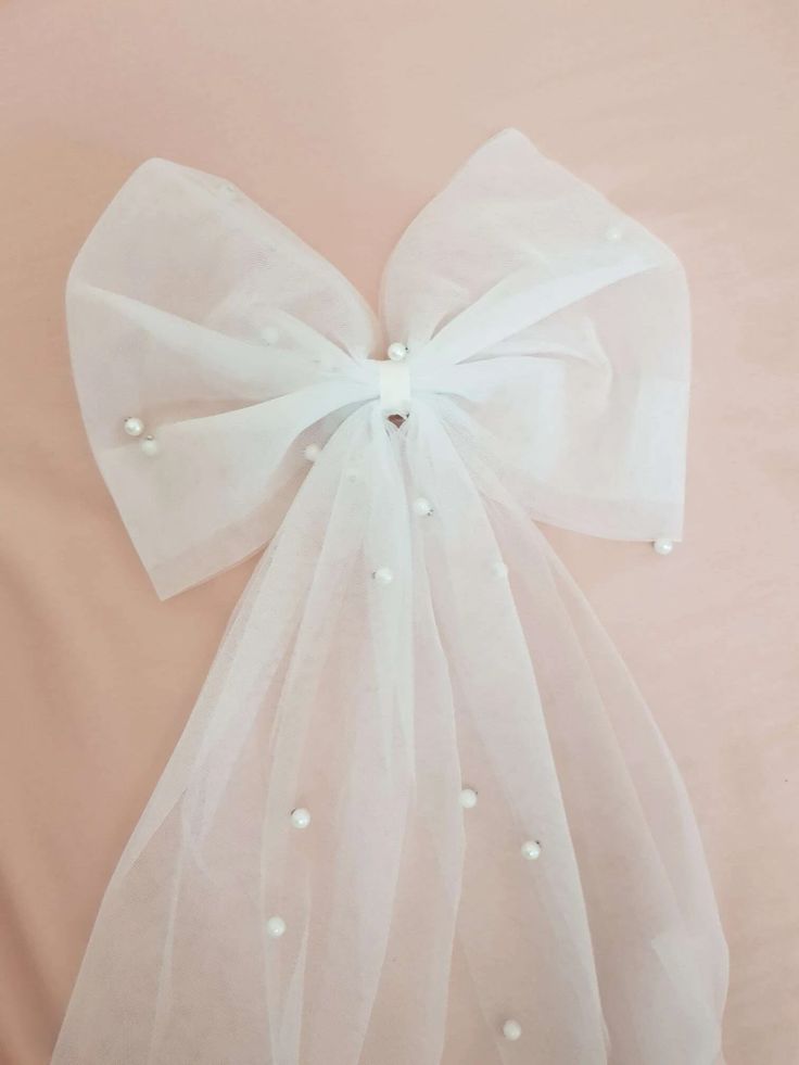 A close up of our Rosie Pearl Bow, showing the mesh veil fabric and scattered pearls. A timeless addition for all bride to be's