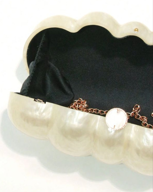 Pearl clutch with a black interior and gold chain on a white background, featuring the brand