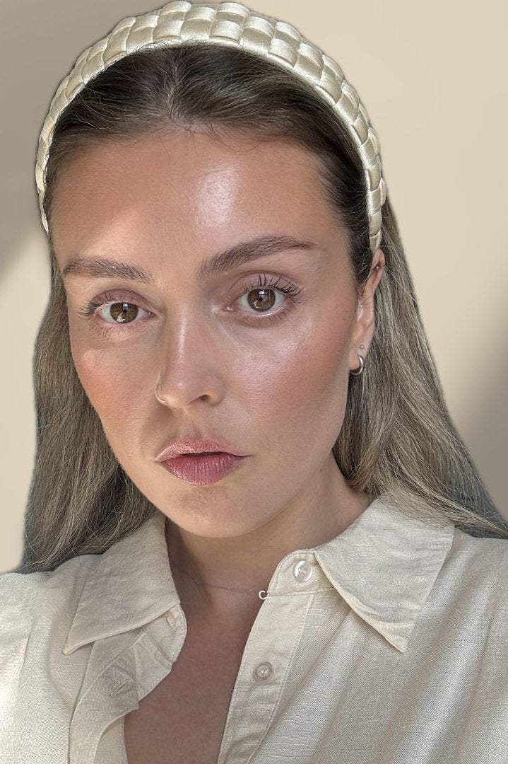 Coral wearing our Beau headband with a cream linen shirt on and neutral background. Our headband in a buttery ivory colour, where the lighting showcases the satin/silk sheen cross-hatch design. Chic and elegant accessory for any bride, hen party or day at the races