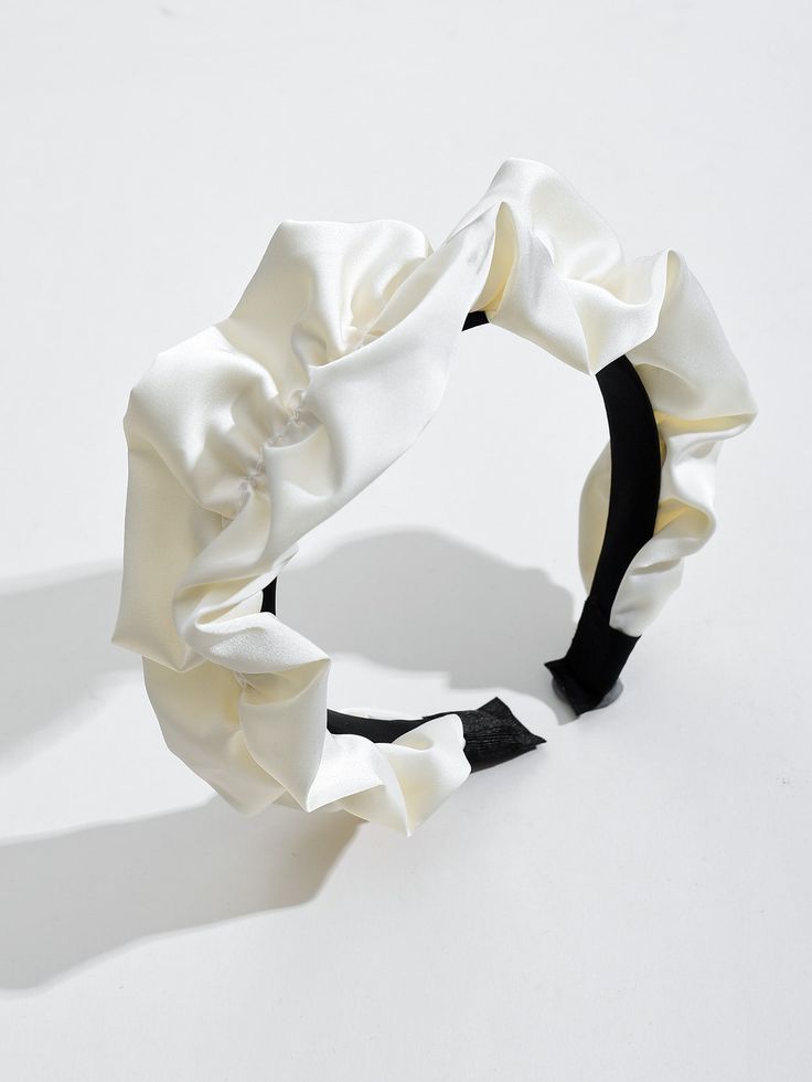 Our Lotus headband against a white background, highlighting the sheen of the soft ruched design and cream silk/satin material across the whole band. Perfect for brides/bridesmaids or adding softness or glamour to any day event