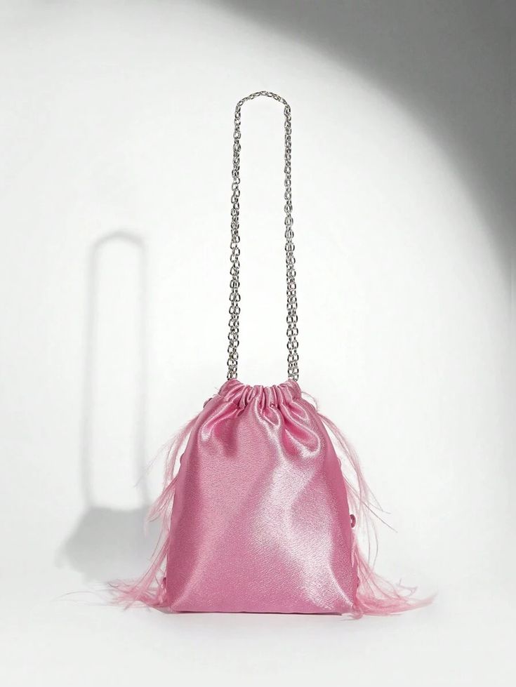 Our Lulu bag against a white background, showing the back of its light pink velvet, drawstring design with soft staggered soft feathers on just the front side, with a medium sized silver chain handle. Perfect for adding a pop of colour to your next outfit