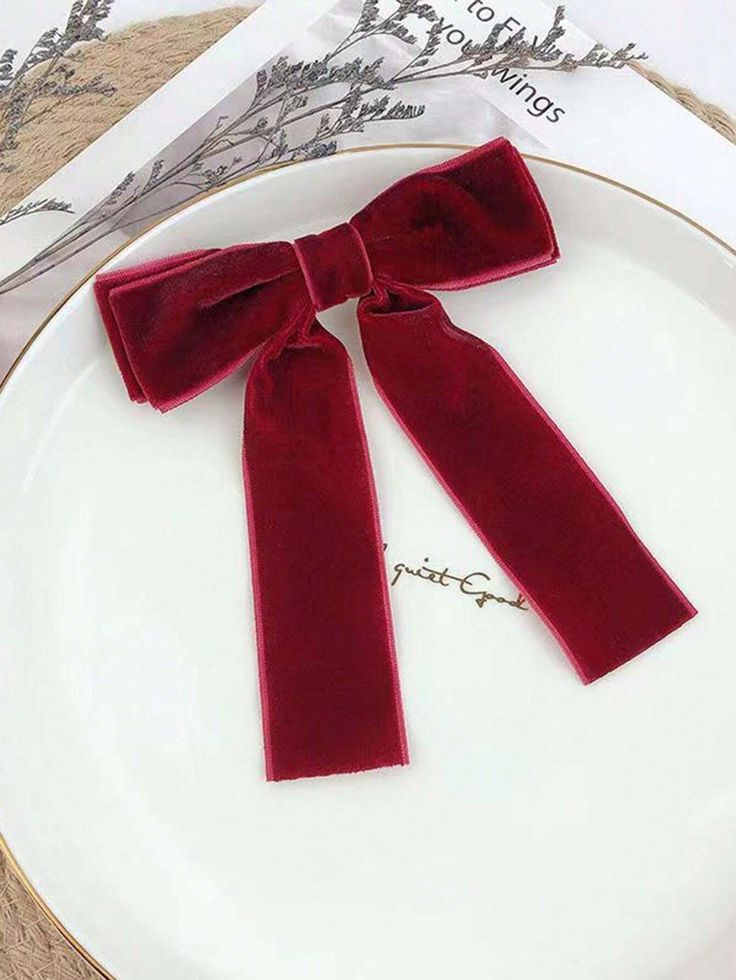 Our Plum velvet bow hair clip, laying flat on a ceramic background. Plush velvet material with a double layer of fabric at the top of the bow. Perfect for a wedding or a formal affair adding a luxurious touch.