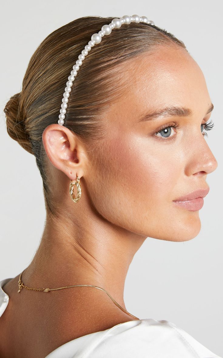 A woman wearing our Remy headband, showing the design of the small continuous pearl band with around 10 slightly larger pearls alternately placed in the middle of the band. A timeless look for any bridal or formal occasion