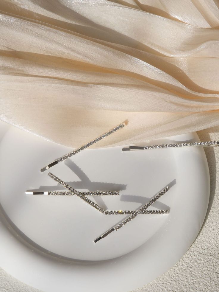Multiple Rhode diamante hair clips against a white and nude material, showing their small size and continuous strip of rhinestone design for added sparkle. Perfect for bride or bridesmaid hair accessories