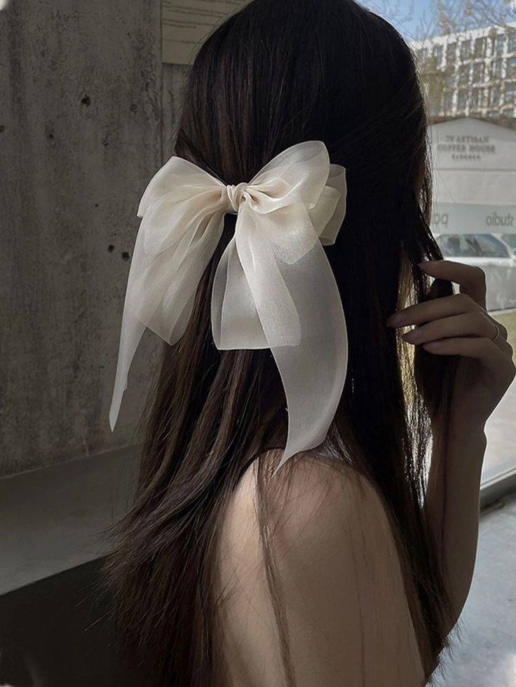 A woman wearing our Sweet Pea Bow Hair Clip, highlighting the softness of the sheer fabric and double layer bow, adding a delicate addition to all brides.