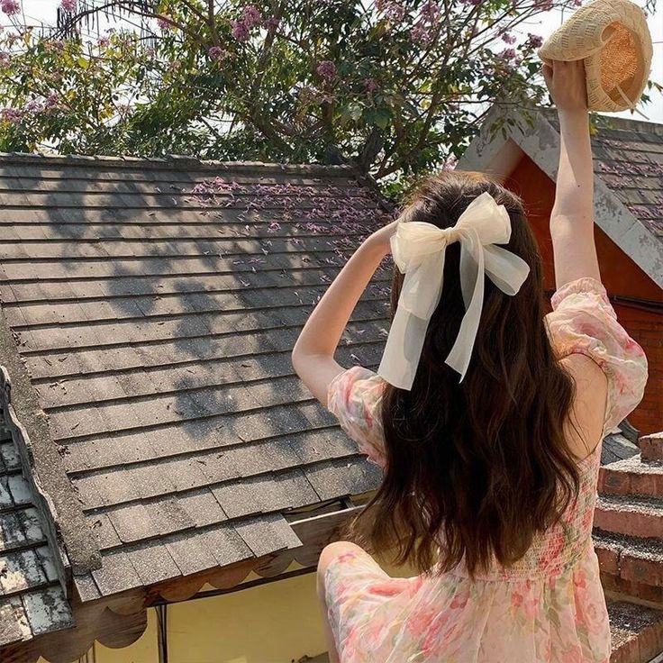 A woman wearing our Sweet Pea Bow Hair Clip in the wind, highlighting the softness of the sheer cream fabric and double layer bow, adding a delicate addition to all brides.