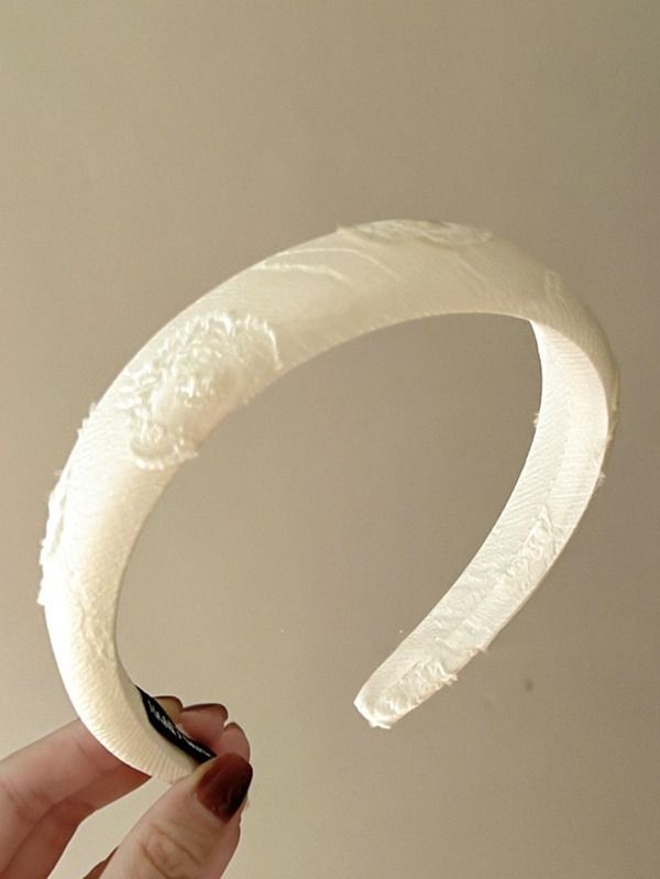 A woman holding our Tulip
Ivory Headband, with Jacquard fabric and delicate floral design. Highlighting the textured fabric, adding softness to any bridal look or day event