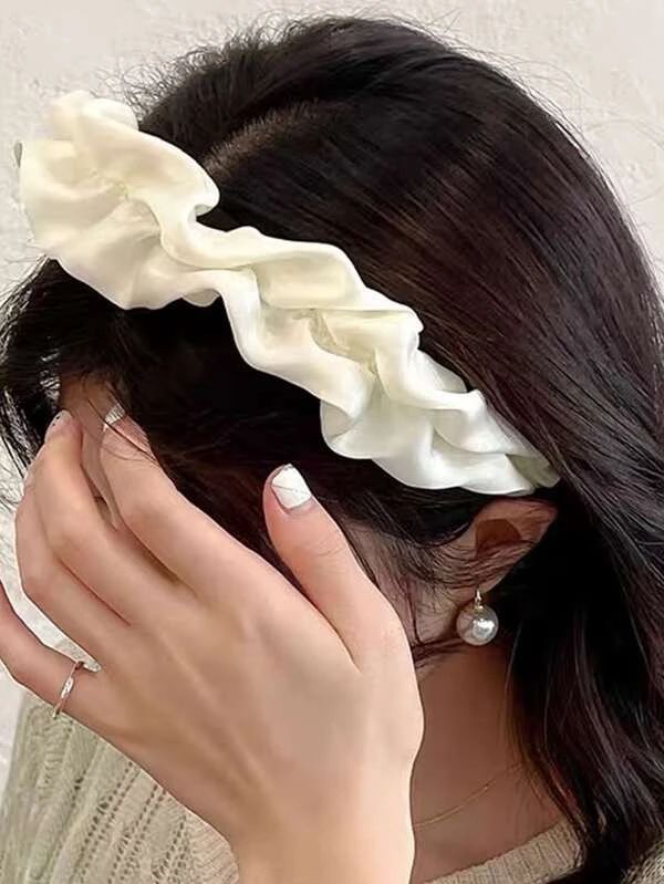 Our Lotus headband being worn by a brunette woman, showing a close up of the soft ruched design and cream silk/satin material across the whole band. Perfect for brides/bridesmaids