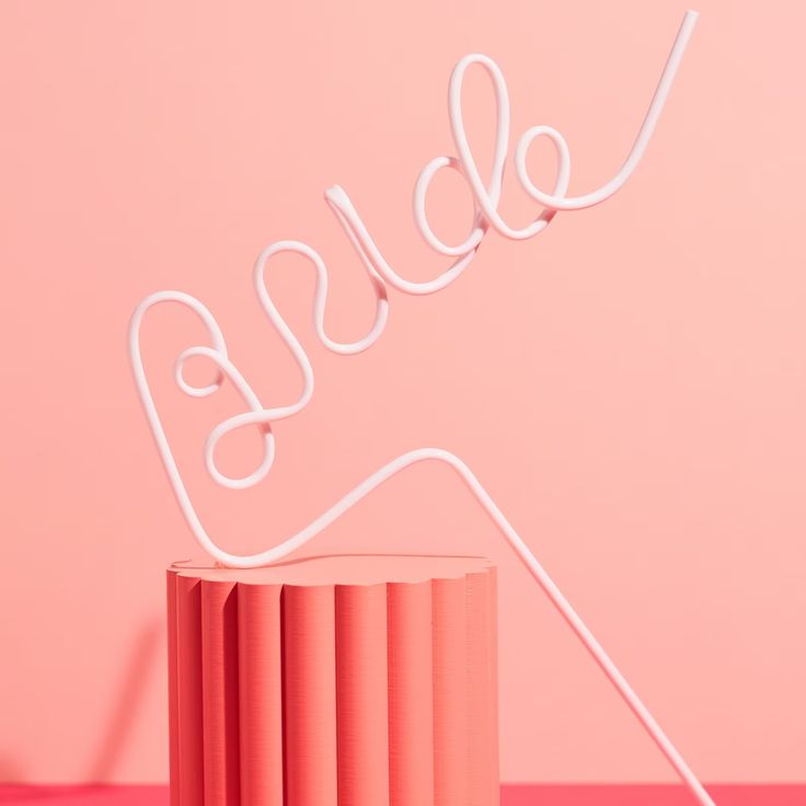 Our white BRIDE straw shown on an angle against a pink wall. Highlighting the colour of the straw with large BRIDE lettering. The perfect fun addition for any bridal or hens celebration