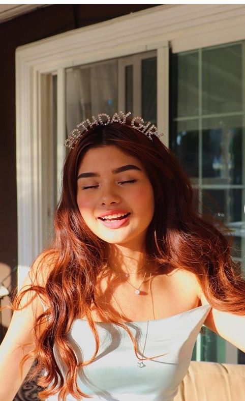 A woman wearing our 'Birthday Girl' diamante headband, smiling in the sunshine. The headband lettering sparkles with diamante rhinestones, adding a glamour to your celebration outfit.