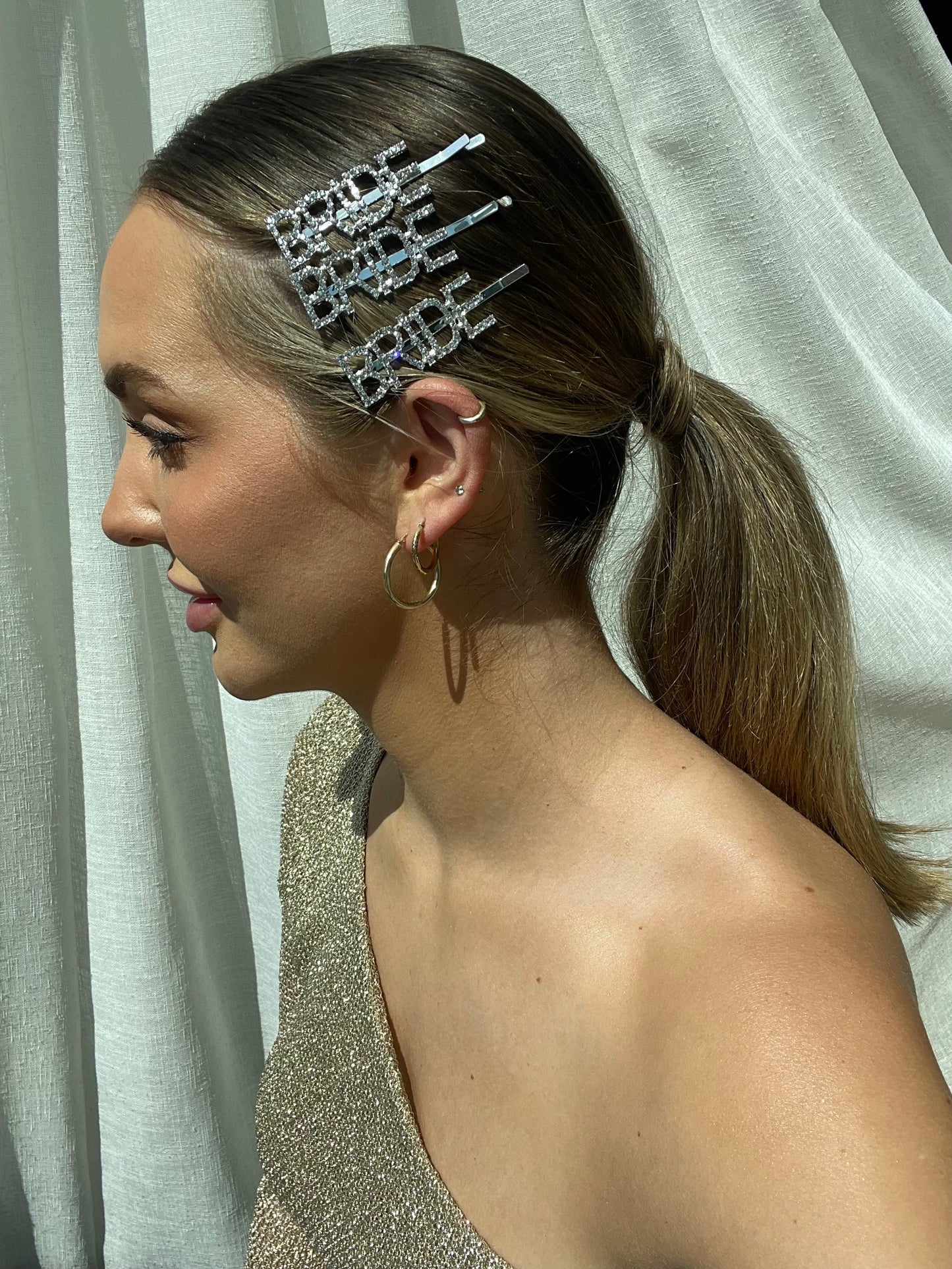 A side profile of a woman wearing 3 of our 'Bride' Diamante silver Hair Clips. Showing how the lettering sparkles and adds glamour to any look, perfect for any bride