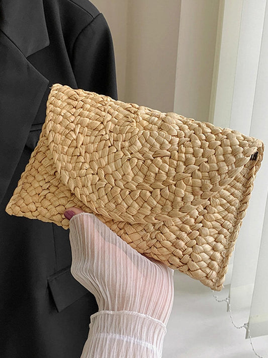 A woman is holding our Amalfi clutch which is made of organic straw material. the perfect bag for holiday.