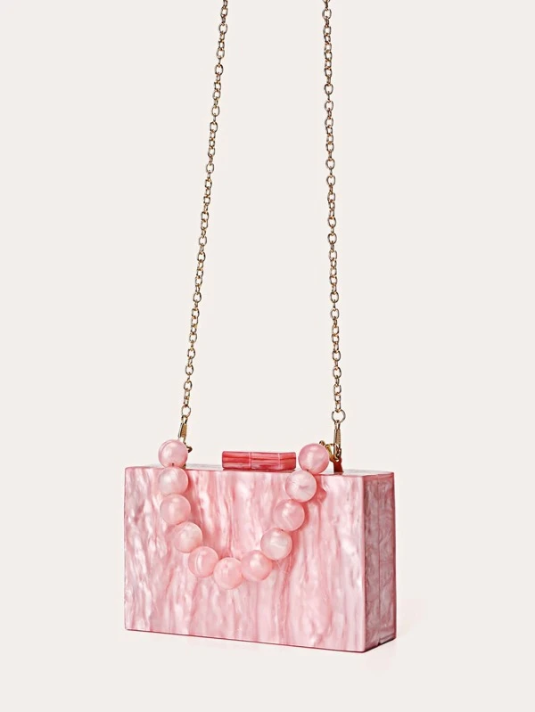 Our marbled pick Candy Acrylic Bag, with the gold chain shoulder attachment hanging and the shorter acrylic beaded handle laying over the side of the bag. Modern rectangular shape adds a statement to your next event