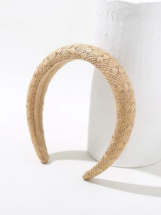 Our Capri headband against a white background highlighting its neutral beige colour. The design is woven across the whole band and made of an organic straw material/raffa. Perfect for casual day events, summery and natural.