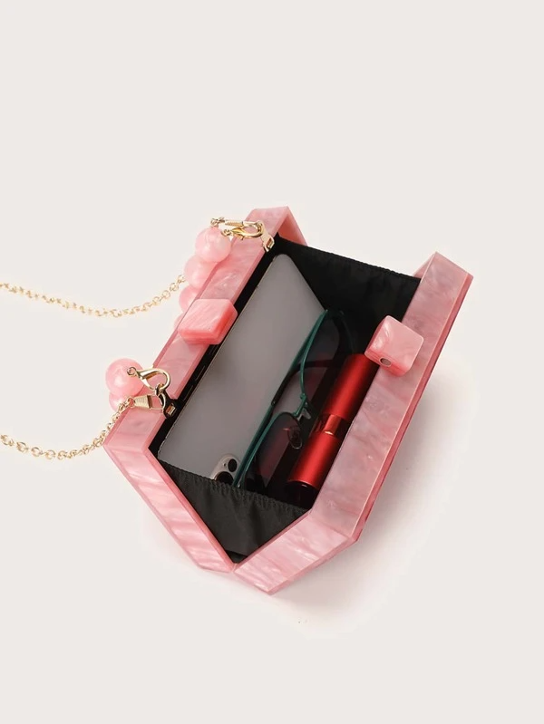 Close-up of our pink Candy Acrylic Bag open, revealing its spacious interior, fitting your smart phone, make up essentials and sunglasses. Showing the clasps magnetic close and longer gold chain over the shoulder attachment. Functional for every event whilst adding a fun pop of colour to your outfit