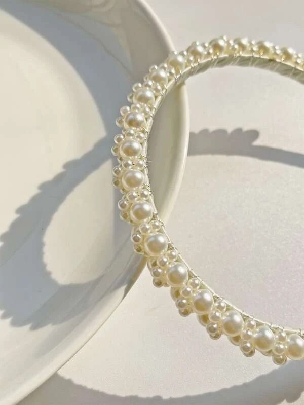 Our Iris Headband shown laying flat and close up of the variously sized pearls clustered around the thin head band. Adds a touch of class to any outfit, brides/bridesmaids, hen parties/wedding day.