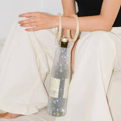 Woman holding our diamante wine bag, with a 750ml wine bottle inside, over the forearm. Circular ivory resin handles, and fully diamante mesh fabric that sparkles. Perfect for any BYO dinner party