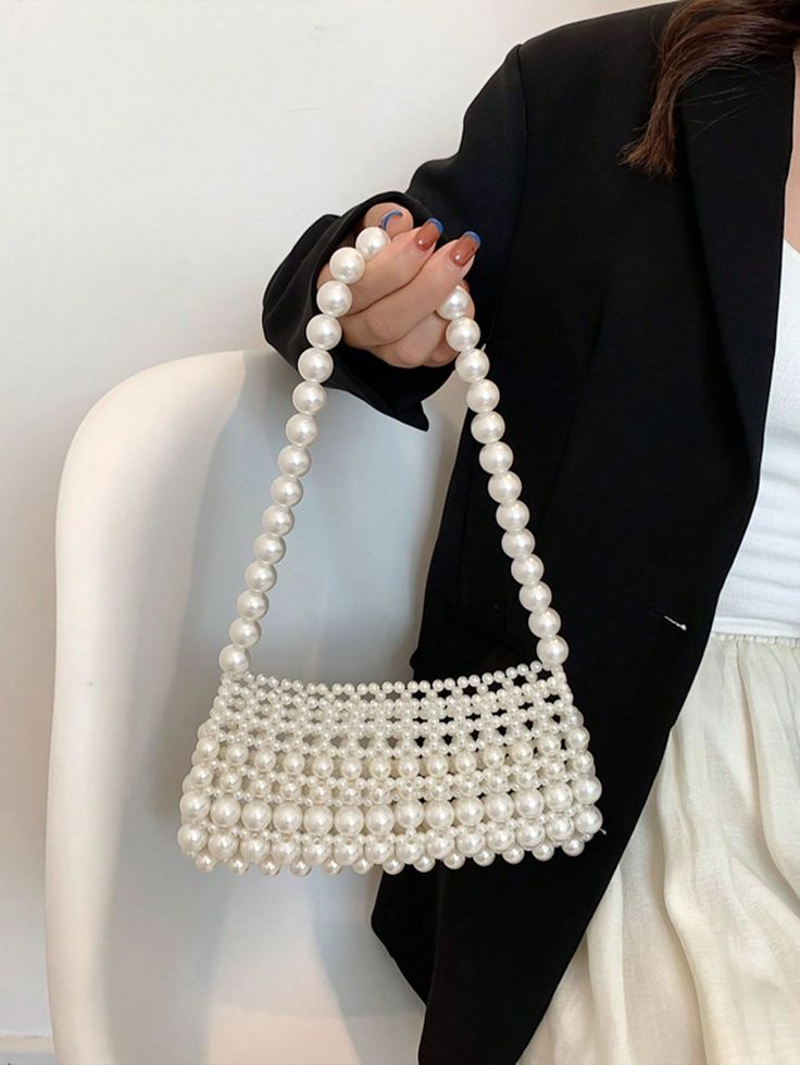 Woman holding our Gigi pearl -adorned handbag, the strap is long enough to go over the shoulder or forearm, completely made out of pearls in different sizes. Compact and perfect for brides or bridesmaids