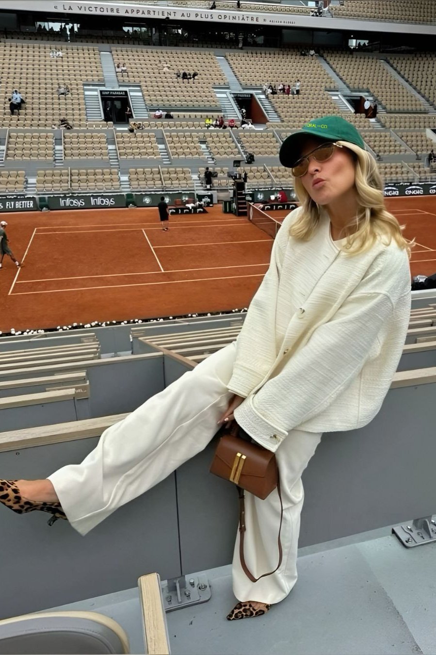 A Woman posing at the tennis wearing our green goddess cap, showing the dark green faded denim and featuring a bold fluro green embroidery. Perfect for casual daily wear or sporting events