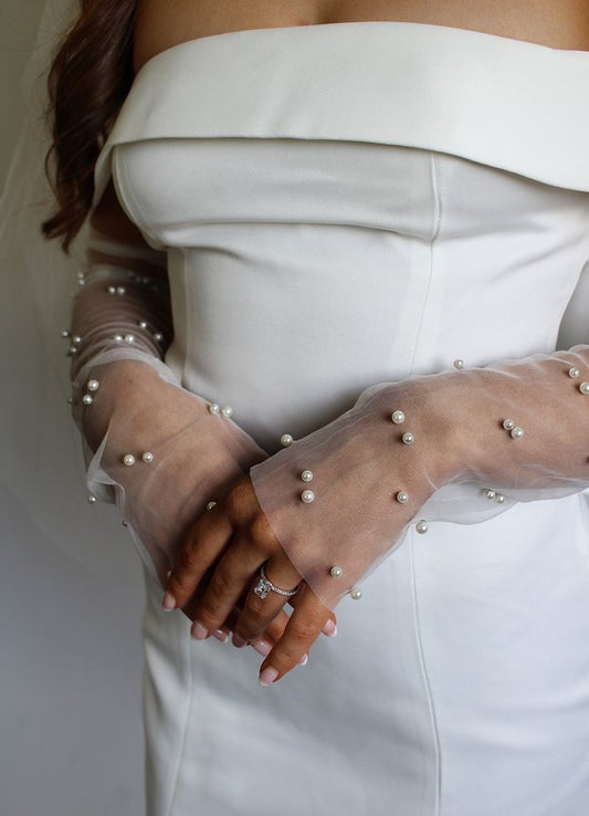 Our Isla gloves being warn by a bride. The delicate sheer mesh material that is embellished with faux pearls adds elegance to their wedding day.