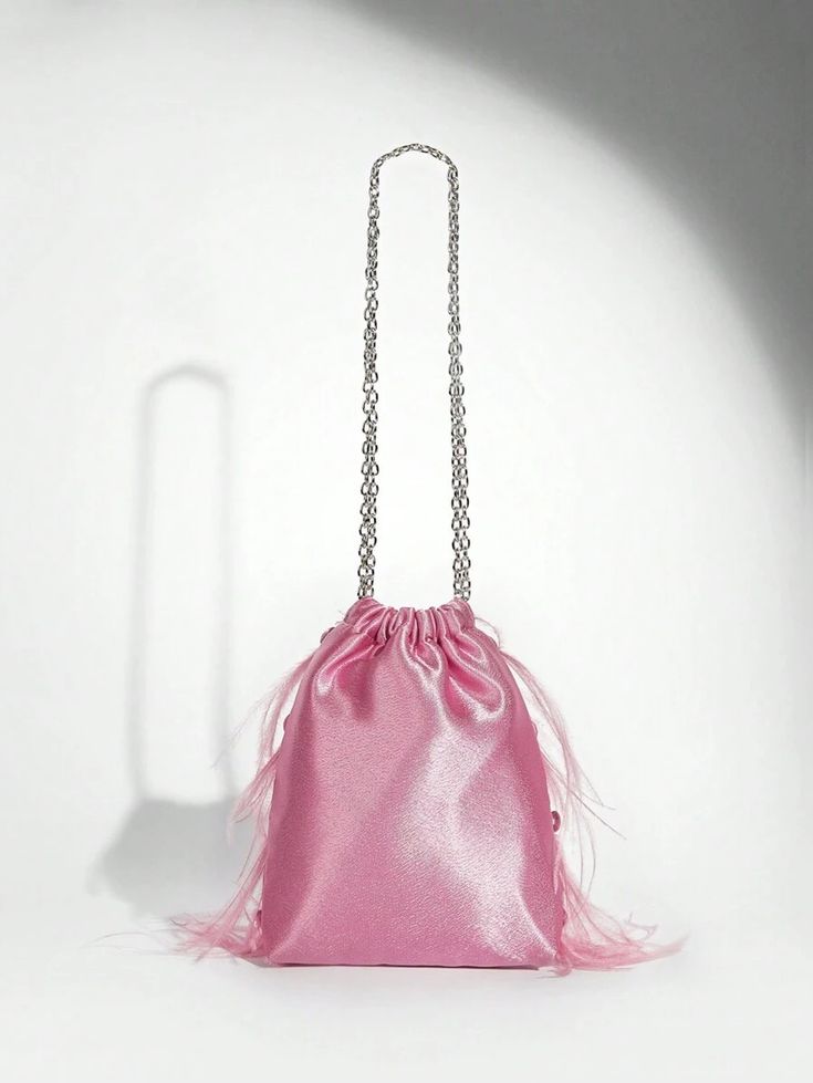 Our Lulu bag against a white background, showing the back of its light pink velvet, drawstring design with soft staggered soft feathers on just the front side, with a medium sized silver chain handle. Perfect for adding a pop of colour to your next outfit 