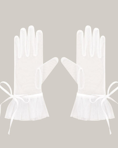 pair of translucent sheer white wedding gloves with a romantic wrist bow and frilled edges, styled for a chic drama or Bridgerton-inspired bridal aesthetic.