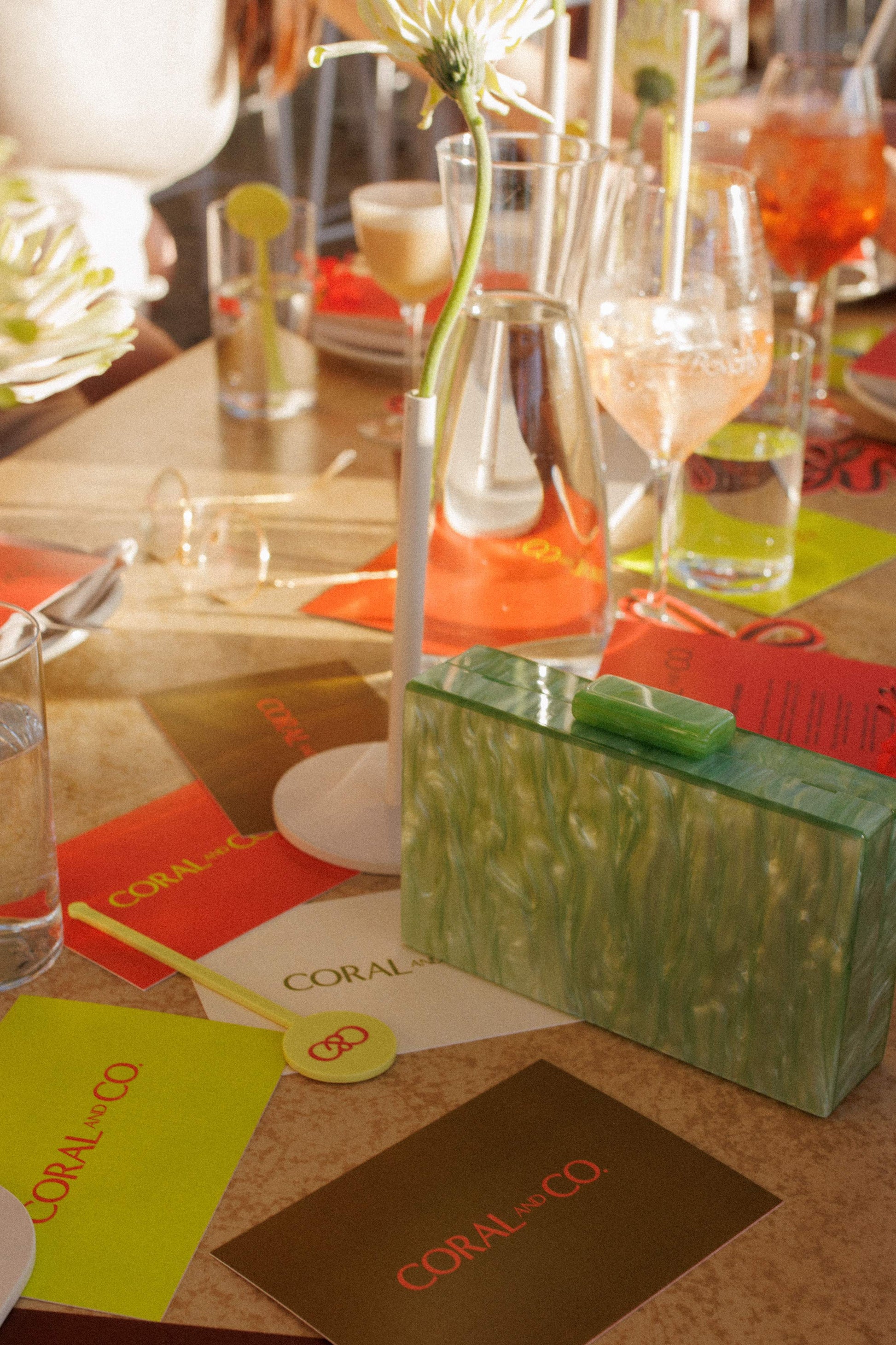 Our rectangular Mint acrylic resin clutch bag shown amongst Coral and Co branded cards in a table setting. Perfect pop of colour to your outfit for your next evening event