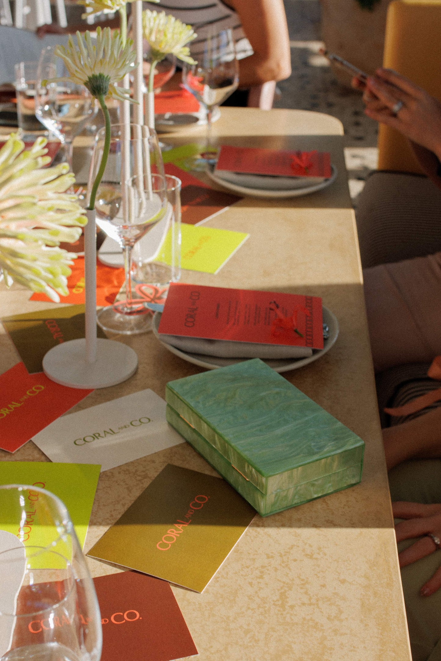 Our rectangular Mint acrylic resin clutch bag shown amongst Coral and Co branded cards in a table setting. Perfect pop of colour to your outfit for your next date night