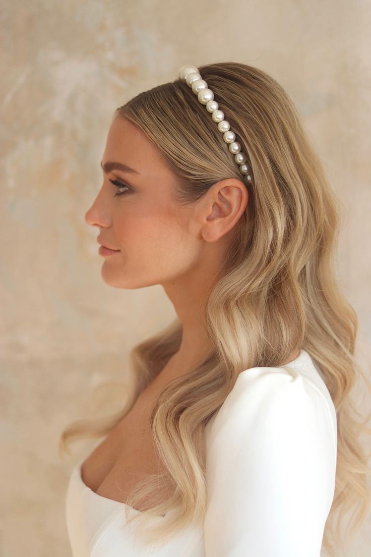 A blonde woman wearing our Orchid headband, the pearls increase in size across the band, where they are smallest at the ends and biggest at the middle. Elevating your bridal look on your wedding day