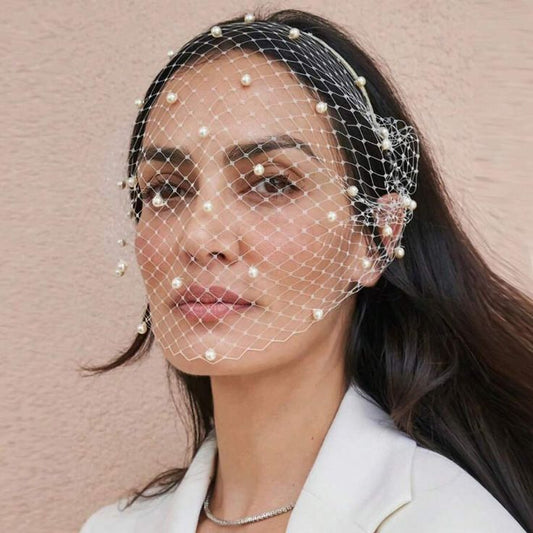 A brunette woman wearing our Paris Veil Headband, showing the white birdcage veil covering the face with delicate netting and pearl detailing. Perfect for brides on their wedding day for timeless looks.