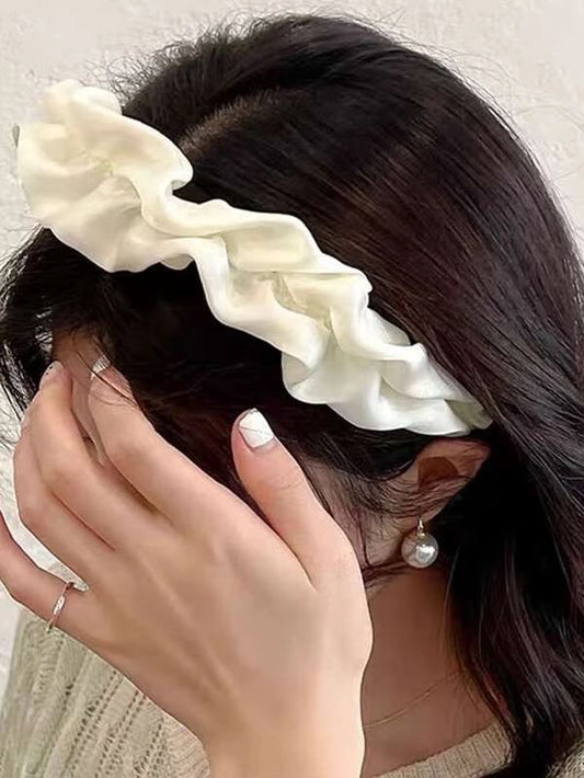 Our Lotus headband being worn by a brunette woman, showing a close up of the soft ruched design and cream silk/satin material across the whole band. Perfect for brides/bridesmaids 