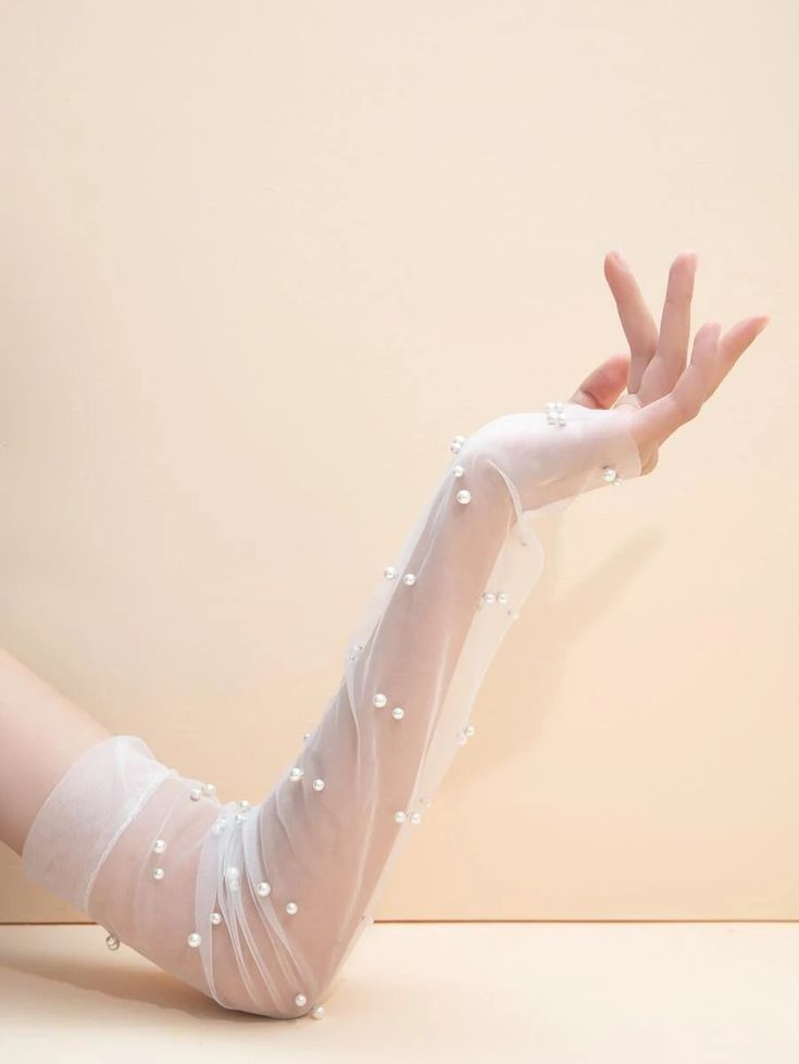 Our Isla gloves shown close up on a womans arm. The delicate sheer mesh material that is embellished with faux pearls adds elegance to their wedding day. Perfect for brides.